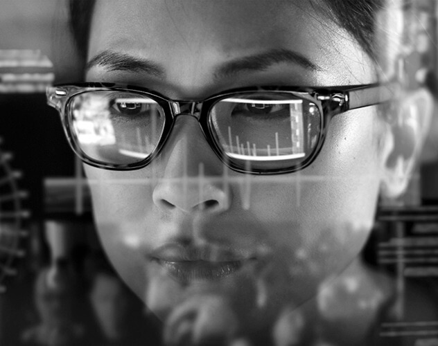 A woman with glasses focused on a computer screen.