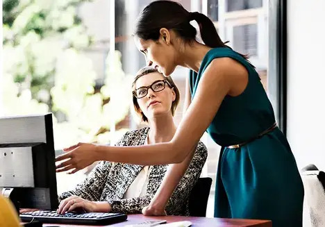 Woman showing something on the screen while another woman listens attentively